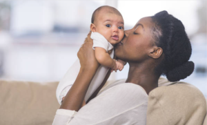 Mother kissing baby in a safe car capsule - best baby capsule hire melbourne